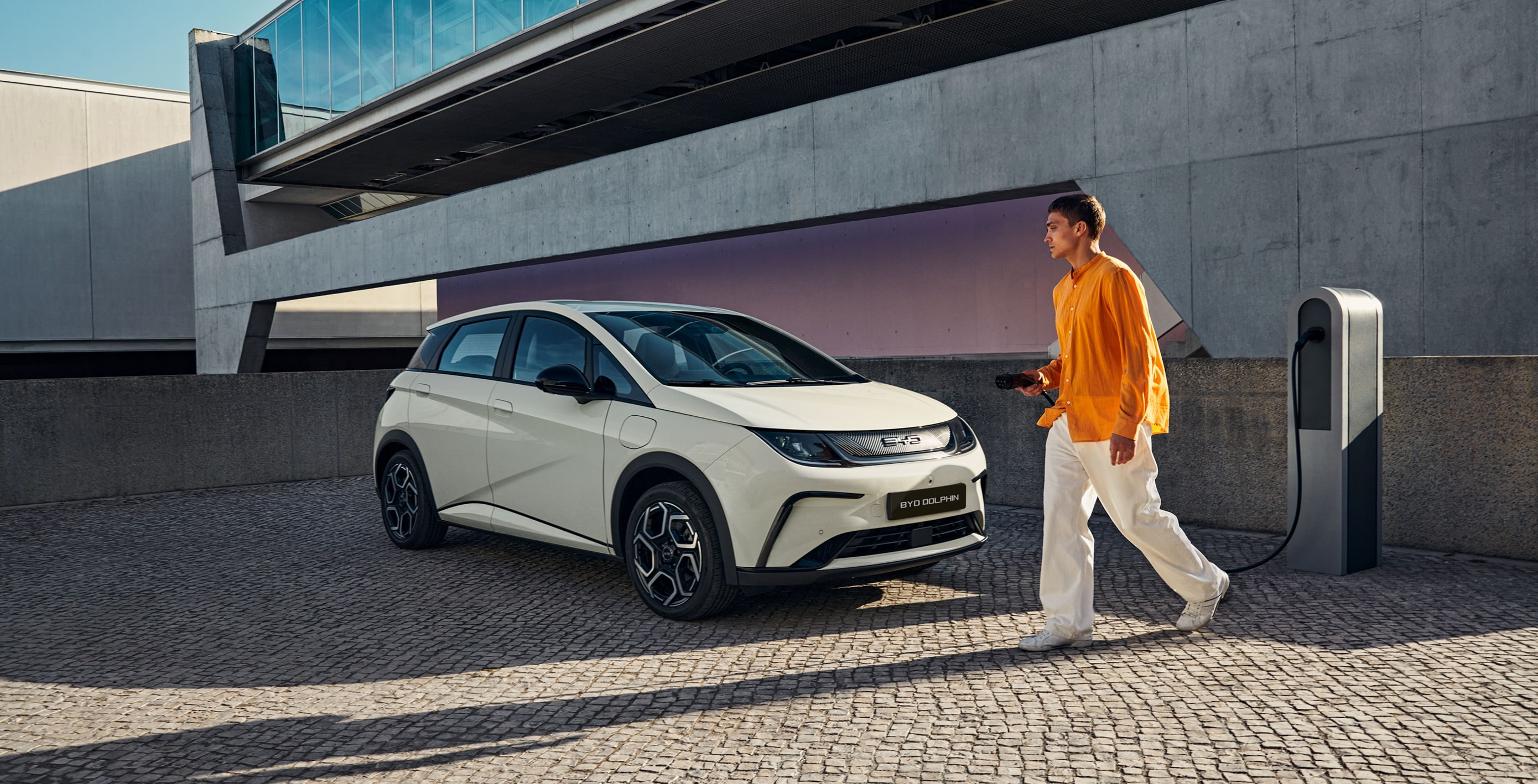 BYD Dolphin blanc branché à une borne de recharge électrique